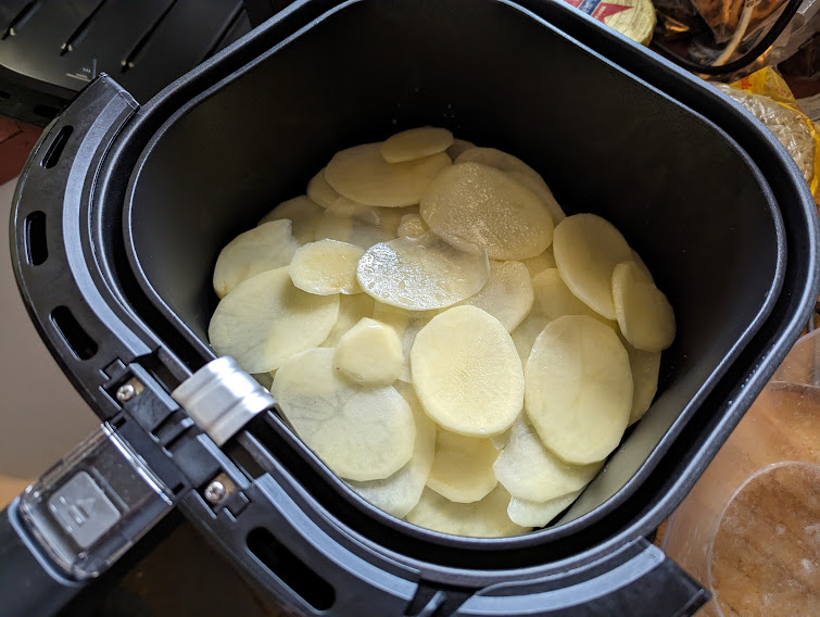 Raw sliced potato in an airfryer basket