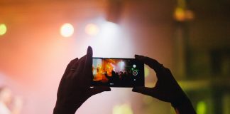 person holding smartphone while taking videos at live concert