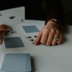 person holding playing cards on white table