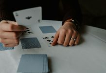 person holding playing cards on white table