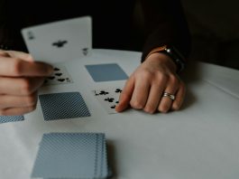 person holding playing cards on white table