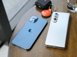 two cell phones sitting on top of a wooden table