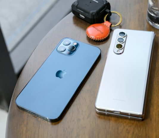 two cell phones sitting on top of a wooden table