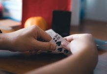 a person holding a piece of paper with playing cards on it