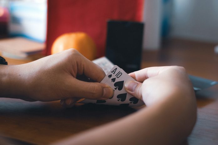 a person holding a piece of paper with playing cards on it