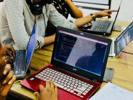 person using black and red Acer laptop computer on table