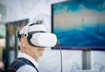 A man wearing a virtual reality headset in front of a laptop