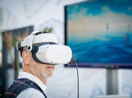 A man wearing a virtual reality headset in front of a laptop