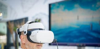 A man wearing a virtual reality headset in front of a laptop
