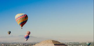 a group of hot air balloons flying over a pyramid