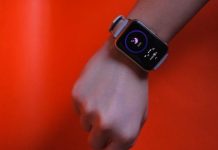 Top Wearable Gadgets for Personal Health Monitoring: Track Your Well-Being with Ease Fist wearing a smartwatch with fitness tracking display on a vibrant orange background.